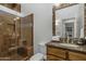 Bathroom showcasing a decorative mirror, wood cabinets, granite countertops, and a tiled shower with a seat at 9154 E Sunflower Ct, Scottsdale, AZ 85266