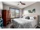 Comfortable bedroom features a large window, upholstered headboard, ceiling fan, and wood dresser at 2425 W Bronco Butte Trl # 2028, Phoenix, AZ 85085