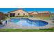 Backyard view showcasing a refreshing pool with elegant stone surround and meticulously maintained green lawn at 34463 N Karan Swiss Cir, San Tan Valley, AZ 85143