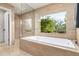 A lavish bathroom offering a soaking tub with garden views and a separate glass enclosed shower at 3901 E San Miguel Ave, Paradise Valley, AZ 85253