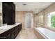 Modern bathroom with a soaking tub, dual sinks, dark cabinets, and beautiful neutral tiling at 3901 E San Miguel Ave, Paradise Valley, AZ 85253