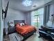 Cozy bedroom features wood floors, large window, decorative lighting, and flat screen television at 44182 W Juniper Ave, Maricopa, AZ 85138