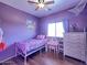 Bright purple bedroom with ceiling fan, window with blinds, and white dresser at 44182 W Juniper Ave, Maricopa, AZ 85138