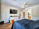 This main bedroom features wood floors, a ceiling fan, and a large TV at 44182 W Juniper Ave, Maricopa, AZ 85138