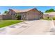 Beige single-story home showcasing a two-car garage, tile roof, manicured lawn, and mature landscaping at 4940 S Rosemary Dr, Chandler, AZ 85248