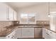 Bright kitchen features white cabinets, mosaic backsplash, stainless steel dishwasher and granite countertops at 4940 S Rosemary Dr, Chandler, AZ 85248