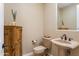 Charming powder room featuring a pedestal sink, decorative mirror, and a wooden cabinet at 12976 W Plum Rd, Peoria, AZ 85383
