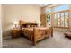 Cozy bedroom with a rustic wooden bed frame, carpet flooring, and ample natural light at 12976 W Plum Rd, Peoria, AZ 85383