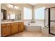 Bright bathroom featuring a corner tub, glass block windows, double sinks, and a shower at 12976 W Plum Rd, Peoria, AZ 85383