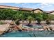 Lush backyard with rock waterfall flowing into spa; features include mature landscaping, palm trees and privacy at 12976 W Plum Rd, Peoria, AZ 85383