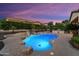 Backyard with freeform pool illuminated with underwater lights, landscaping, and privacy at 12976 W Plum Rd, Peoria, AZ 85383