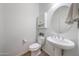 Bathroom with a pedestal sink, round mirror, toilet, and vanity storage at 16229 W Berkeley Rd, Goodyear, AZ 85395