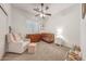 Bedroom with neutral carpet, ceiling fan, natural light, and a glider chair with crib at 16229 W Berkeley Rd, Goodyear, AZ 85395