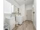 Modern laundry room with wood look flooring, new washer and dryer, sink and white cabinets at 16229 W Berkeley Rd, Goodyear, AZ 85395