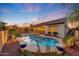 Backyard pool with baja shelf, rock features, string lights, and landscaping at 16229 W Berkeley Rd, Goodyear, AZ 85395