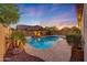 Backyard pool with baja shelf, rock features, string lights, and landscaping at 16229 W Berkeley Rd, Goodyear, AZ 85395