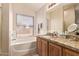 Bright bathroom features a bathtub, vanity with granite countertop, and a large window at 16274 N 138Th Ln, Surprise, AZ 85374