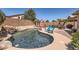 Sparkling pool featuring a rock waterfall feature, desert landscaping, outdoor seating, and privacy fence at 17244 W Mohave St, Goodyear, AZ 85338
