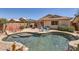 Inviting backyard pool with rock features, desert landscaping, outdoor seating, and mature tropical trees at 17244 W Mohave St, Goodyear, AZ 85338