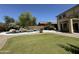 Green backyard with a pool, turf, palm trees, patio, and charming desert landscaping at 20426 N Alma Dr, Maricopa, AZ 85138