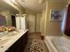 Bright bathroom featuring dual sinks, a tub, and tile flooring with decorative rug at 20426 N Alma Dr, Maricopa, AZ 85138
