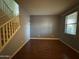 Cozy living room with a staircase, hardwood floors, a large window, and a minimalist aesthetic for a modern, comfortable feel at 20426 N Alma Dr, Maricopa, AZ 85138
