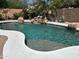 Beautiful swimming pool with a step entry surrounded by mature desert landscaping and a rock waterfall at 20426 N Alma Dr, Maricopa, AZ 85138