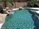 Relaxing pool with rock waterfall and desert landscaping creating a private backyard oasis for enjoying the sunshine at 20426 N Alma Dr, Maricopa, AZ 85138