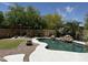 Resort style pool with rock waterfall feature, pergola with seating, and lush landscaping at 20426 N Alma Dr, Maricopa, AZ 85138