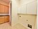 Bright laundry room offering tile floors, wood cabinets, and white storage shelves at 20472 W Daniel Pl, Buckeye, AZ 85396