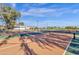 Brightly lit tennis courts offer a place to exercise and enjoy the outdoors with a view of clubhouse and blue skies at 21616 E Calle De Flores --, Queen Creek, AZ 85142