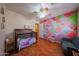 Vibrant Bedroom with colorful geometric wall art, a crib, and hardwood floors at 23104 W Kimberly Dr, Buckeye, AZ 85326