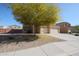 View of a tan two-story home with a mature yellow tree on a stone-covered front yard at 23104 W Kimberly Dr, Buckeye, AZ 85326