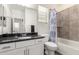 Bathroom featuring a vanity with a black countertop, decorative mirror, and shower-tub combo at 3231 S Mingus Dr, Chandler, AZ 85286