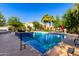 Inviting community pool with clear blue water, lounge chairs, umbrellas, and lush green landscaping at 3231 S Mingus Dr, Chandler, AZ 85286