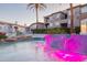 Stunning pool featuring pink illuminated waterfalls, palm trees and nearby residence buildings at 3236 E Chandler Blvd # 3031, Phoenix, AZ 85048
