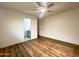 Simple bedroom with wood-look flooring and a ceiling fan, adjacent to a bright bathroom at 344 E Jacaranda St, Mesa, AZ 85201