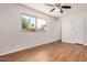 Bright bedroom featuring hardwood floors, a ceiling fan, and a window with backyard views at 4121 W Paradise Dr, Phoenix, AZ 85029