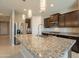 An open kitchen showcasing a large kitchen island, stainless steel appliances, and modern hanging lights at 4215 W Suncup Dr, San Tan Valley, AZ 85144
