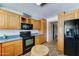 A cozy kitchen featuring wood cabinets, black appliances, and neutral countertops offering a practical cooking space at 5347 W Seldon Ln, Glendale, AZ 85302