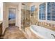 Bathroom featuring a glass shower, soaking tub, and travertine tile at 6767 E Nightingale Star Cir, Scottsdale, AZ 85266