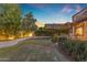 A spacious backyard with decorative landscape beds, plush green lawn, and an expansive tree at 6841 S Roosevelt St, Tempe, AZ 85283