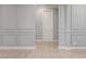 Neutral hallway featuring paneled walls with white trim, and neutral tile flooring leading to a white door at 716 W Blue Ridge Dr, San Tan Valley, AZ 85140