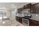 Kitchen featuring dark cabinetry, granite countertops, stainless appliances, tile backsplash, and view to second living space at 716 W Blue Ridge Dr, San Tan Valley, AZ 85140