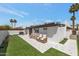 Spacious backyard with artificial grass, tiled patio with seating, and lush palm trees creating a tropical oasis at 7643 E Rancho Vista Dr, Scottsdale, AZ 85251