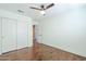 Light bedroom showcasing hardwood floors, a ceiling fan, an closet, and access to another room at 768 E Mountain Sky Ave, Phoenix, AZ 85048