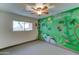 A simple bedroom with a unique mural accent wall and a ceiling fan at 8220 E Montecito Ave, Scottsdale, AZ 85251