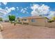 Side view of a single-story home with a gravel yard and wooden fence, under a partly cloudy sky at 8602 N 27Th Ave, Phoenix, AZ 85051