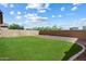 A well-maintained backyard with green grass, decorative rock border, and a tall block wall fence for privacy at 9147 W Minnezona Ave, Phoenix, AZ 85037