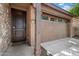 Exterior view featuring a dark brown front door, light-colored garage, and stone wall accents at 9147 W Minnezona Ave, Phoenix, AZ 85037